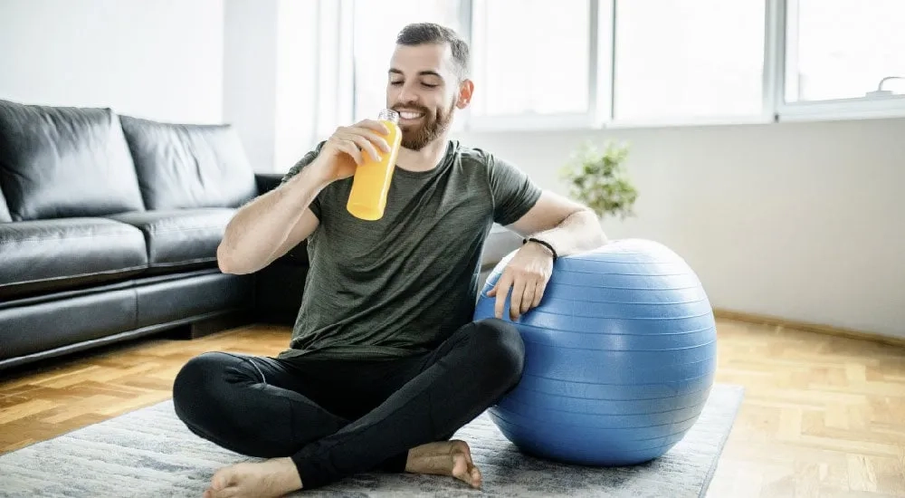Hombre tomando jugo de naranja después del una rutina de ejercicio.