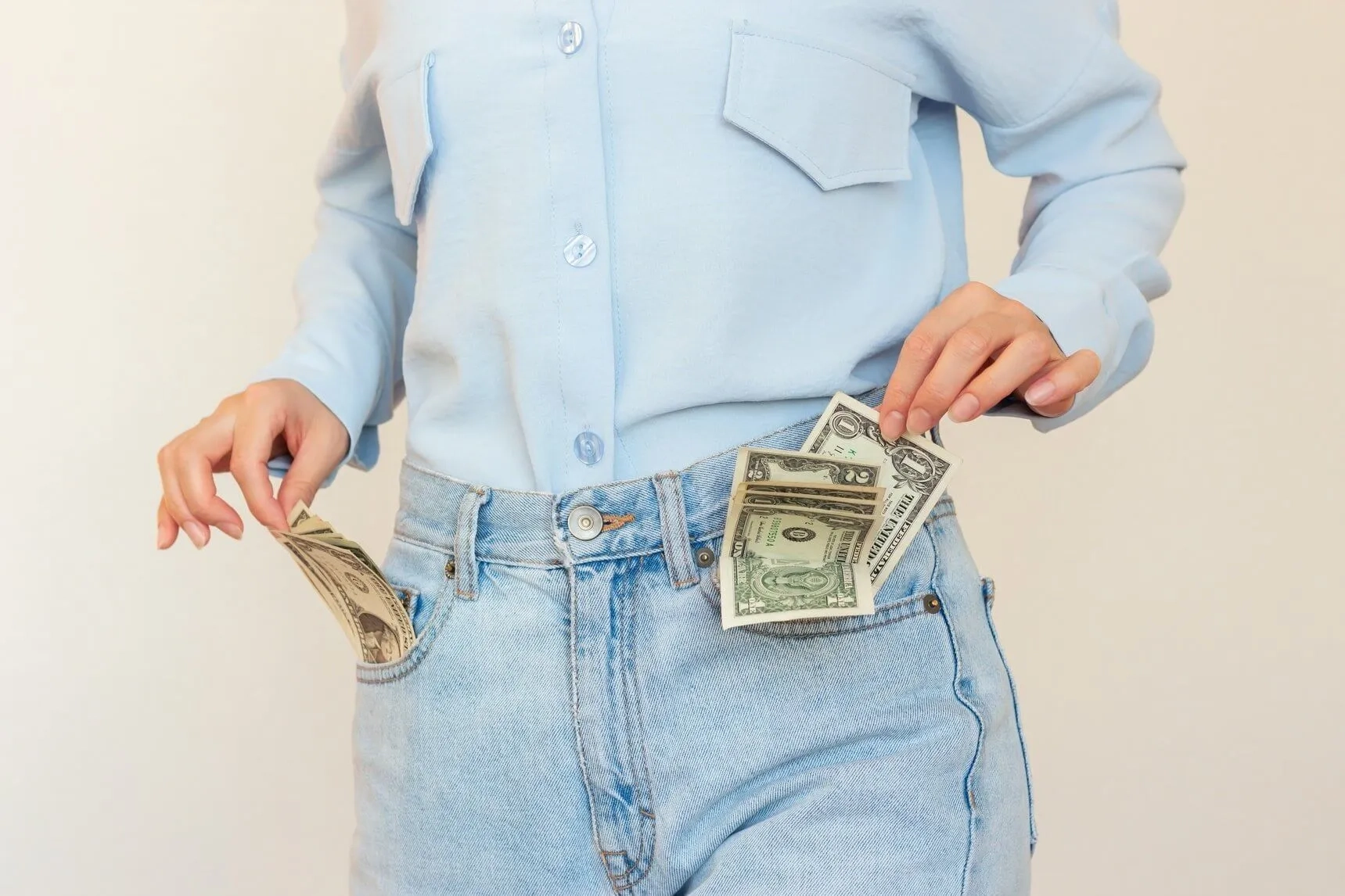Mujer mostrando el dinero de las bolsas del pantalón.